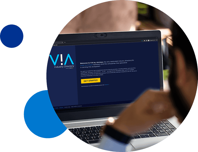 via-circle-inset Person viewing a laptop screen displaying V!A Industry Directory website homepage.