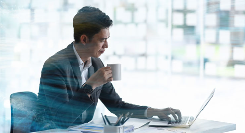 Business professional working on a laptop while holding a coffee cup.