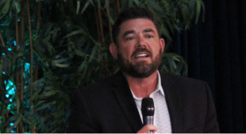 Man speaking into a microphone in a green and black setting.