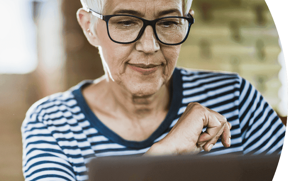 Elderly woman wearing glasses using a laptop.