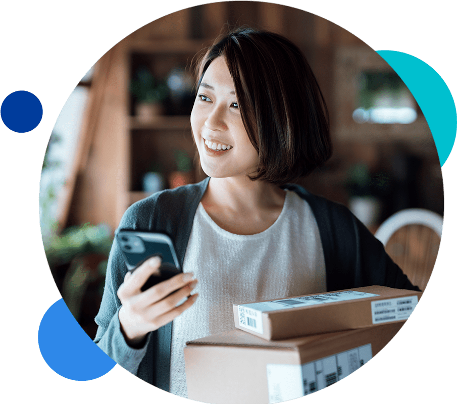 Smiling woman holding smartphone and delivery boxes.