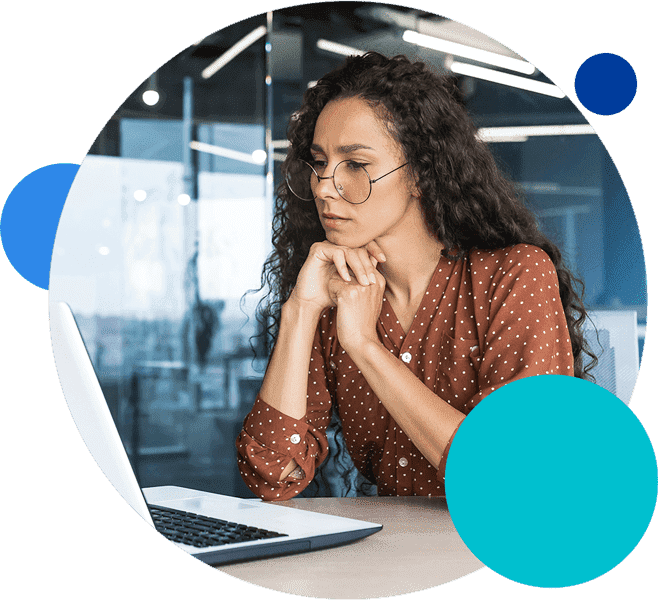 Person with glasses working on a laptop in a modern office setting.
