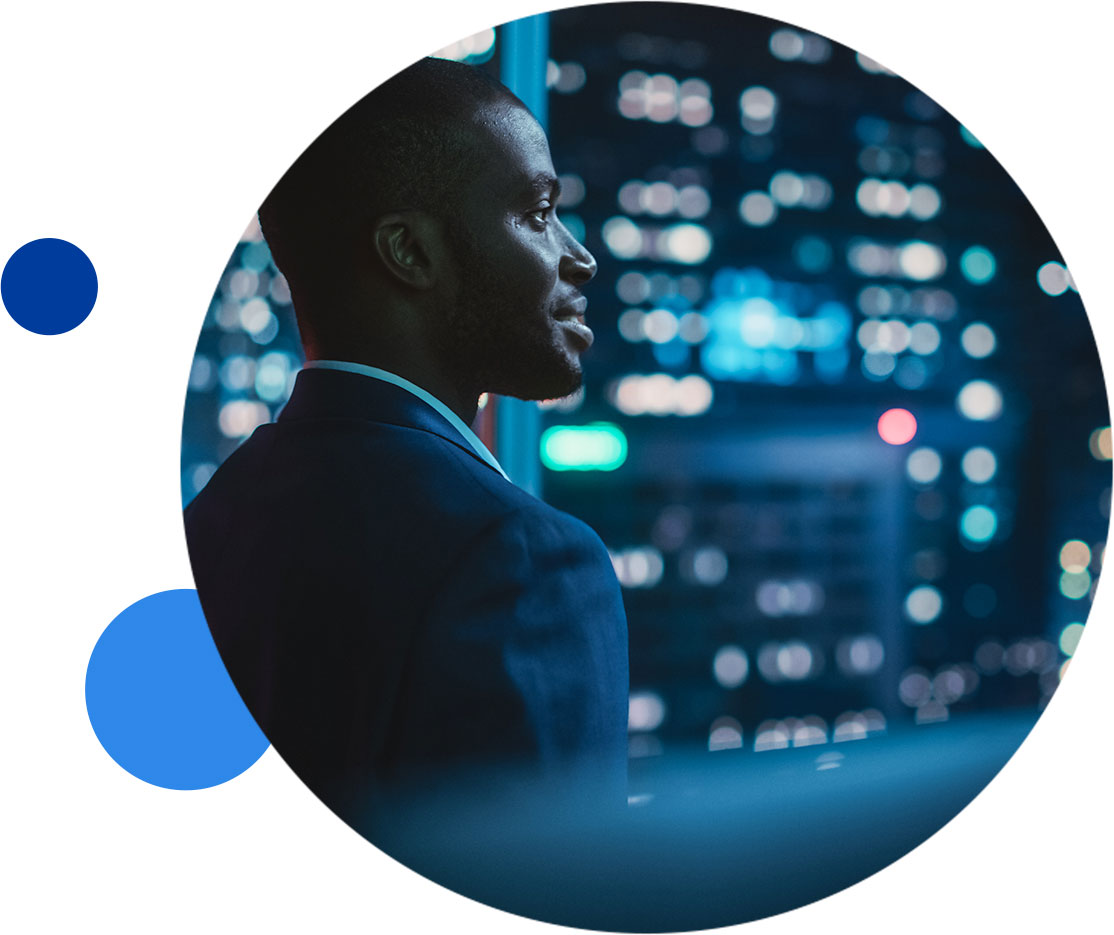 data-licensing-inset Businessman gazing out a window in a cityscape at night.