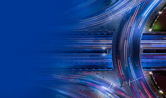 Aerial view of fast-moving traffic on a highway interchange at night.