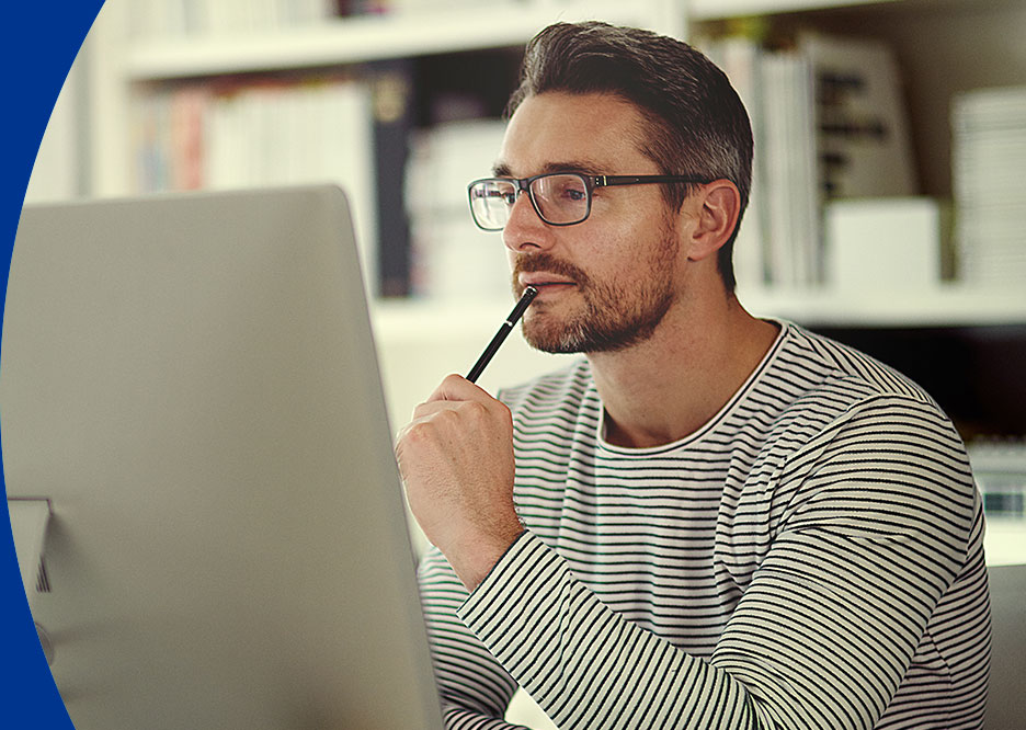 Man in striped shirt thinking while looking at computer screen