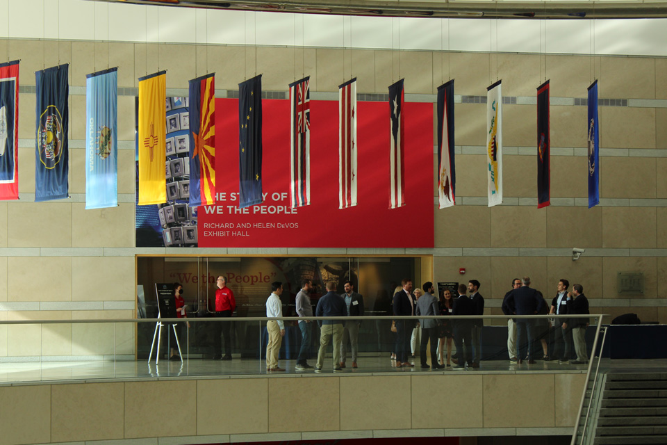 VIA-NatlConstCtr-Event People gathered in a museum exhibit hall with state flags displayed.