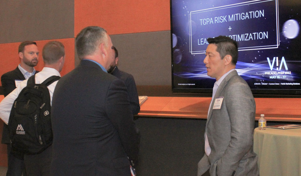 VIA-product-lounge Business professionals networking at a conference with a focus on risk mitigation and lead optimization.