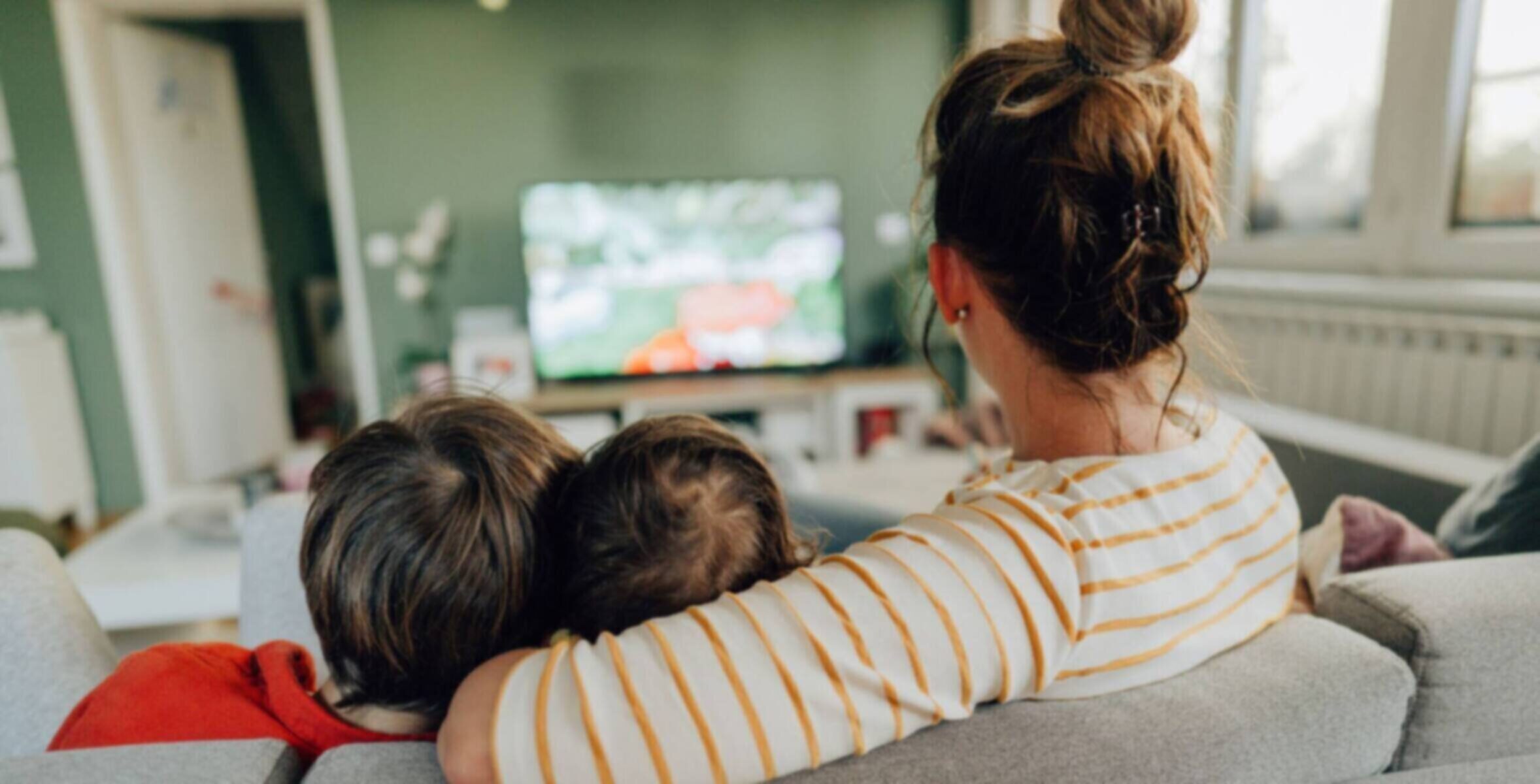 Family relaxing on sofa watching TV together.