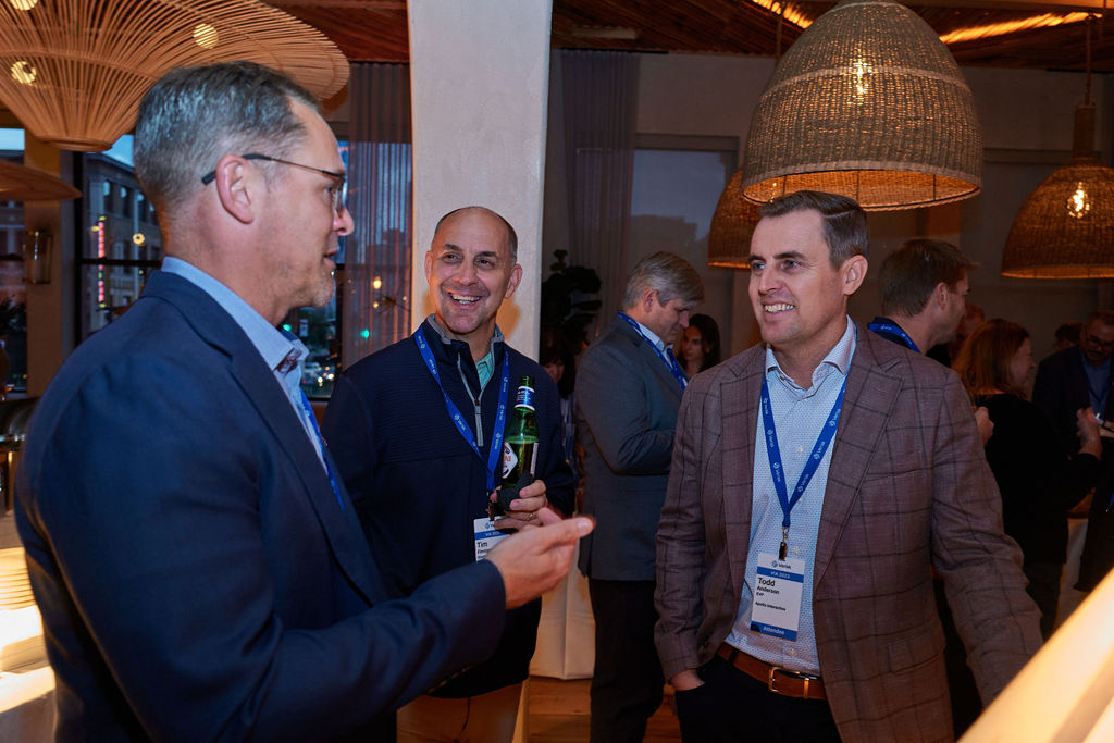 L1090054 Business professionals networking at a corporate event with lanyards visible.