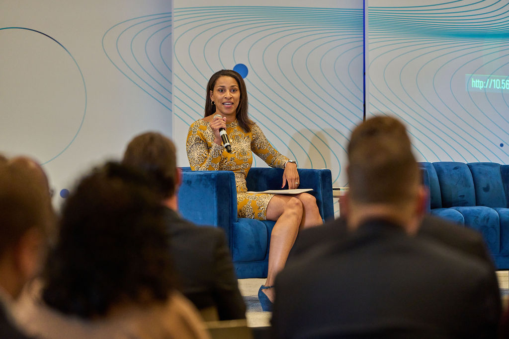 _P1_3579 Woman speaking on stage at a business conference with microphone.