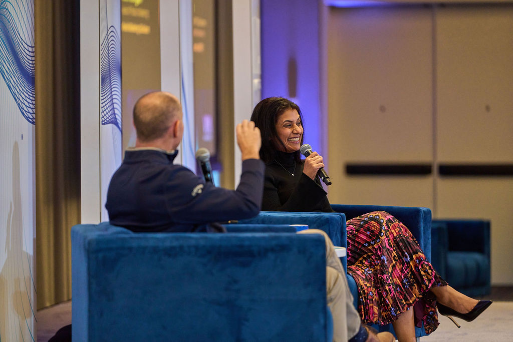 _P1_4014 Two people having a conversation on stage during a conference, holding microphones.