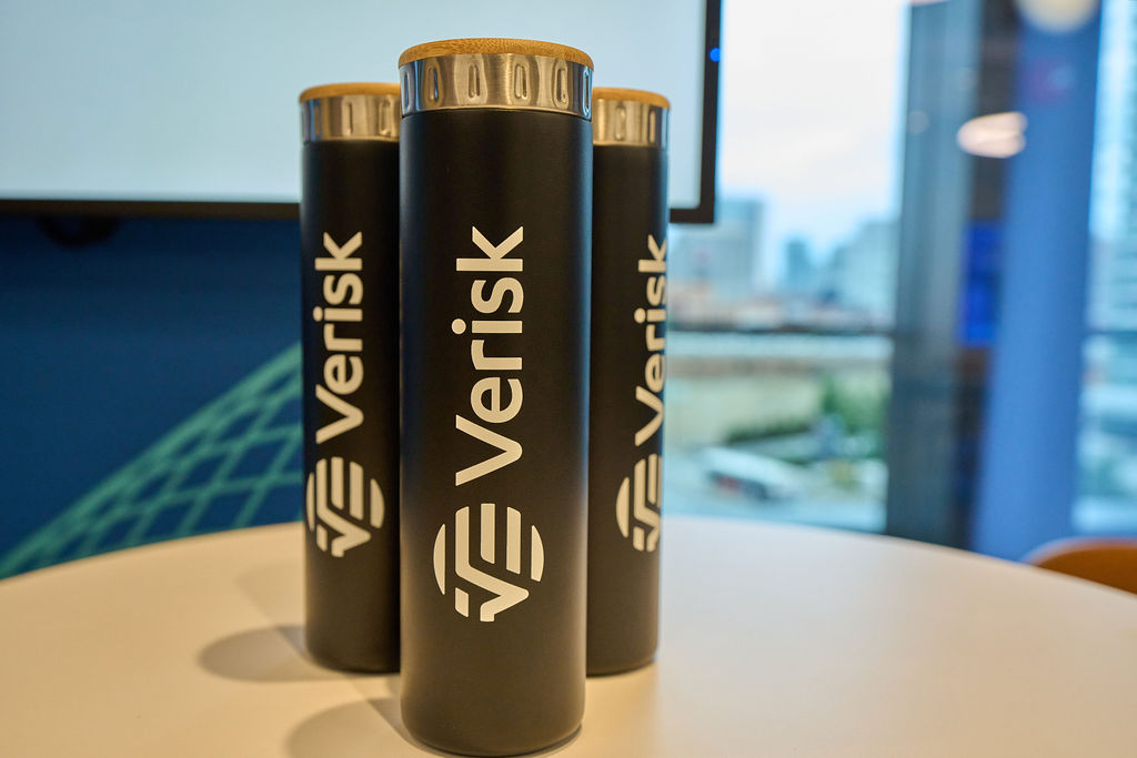 _P2_7947 Three black Verisk-branded water bottles on a table in an office setting.