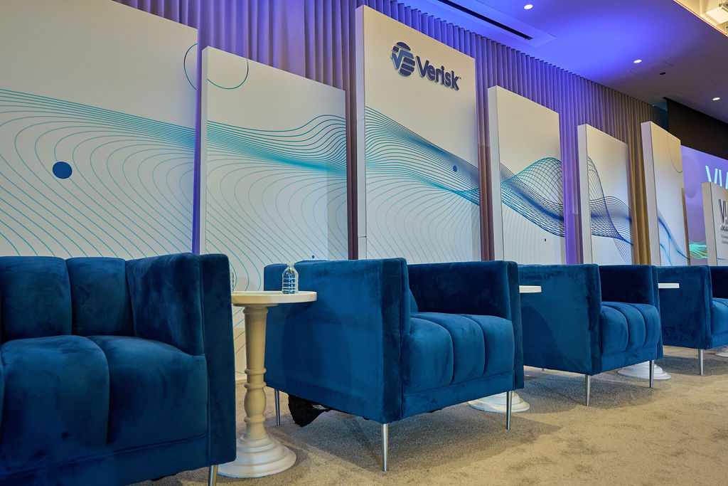 _P2_8023 Blue velvet chairs arranged in front of a modern conference backdrop.