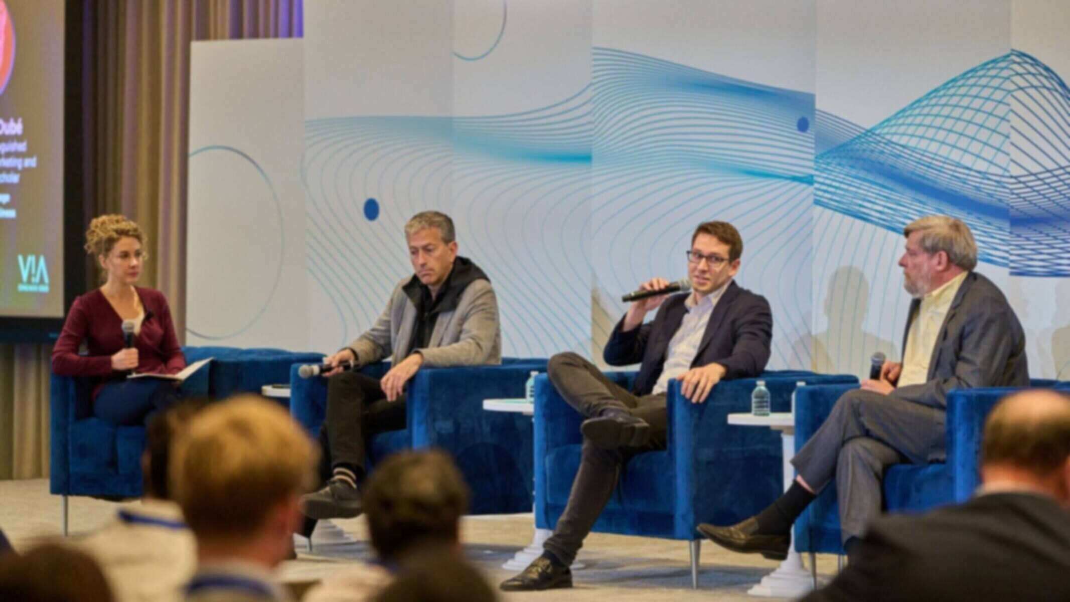 Panel discussion with four speakers on stage at a conference.