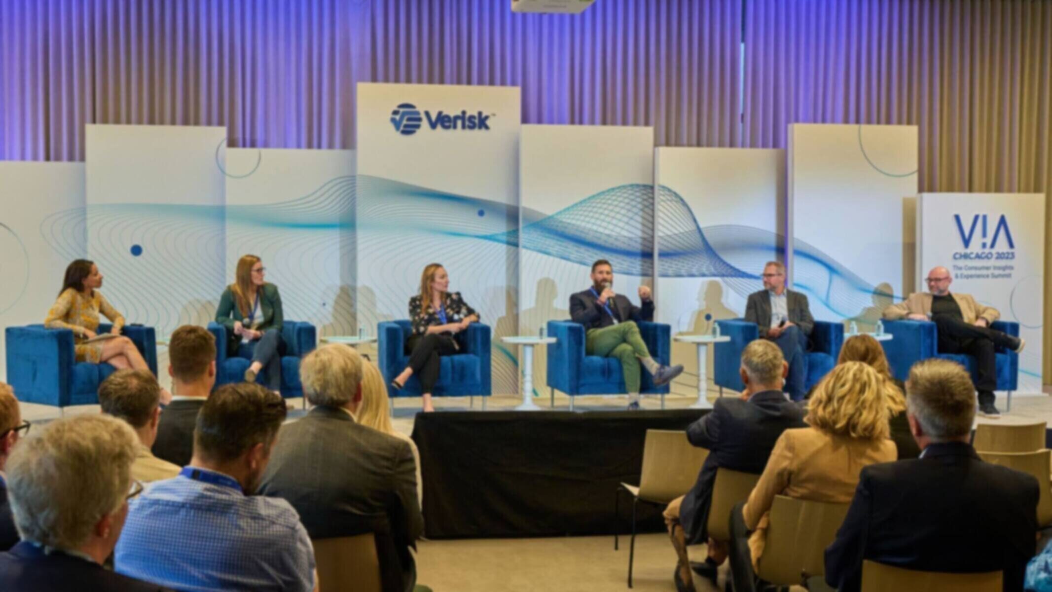 Panel discussion at VIA Chicago 2023 with Verisk branding in the background.