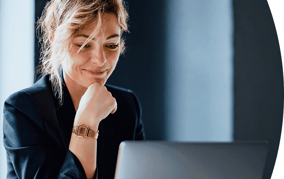 Smiling woman working on a laptop in a modern office setting.