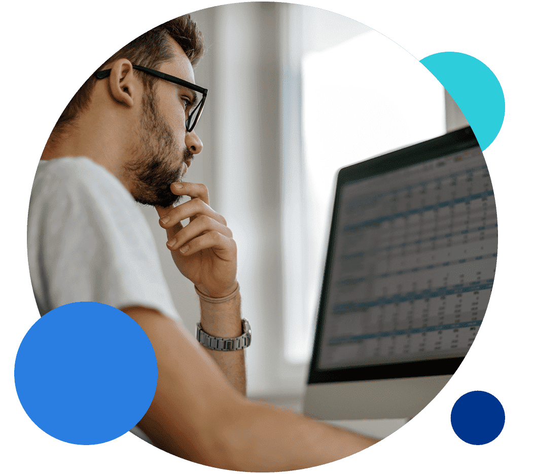 Man analyzing data on a computer screen in an office setting.