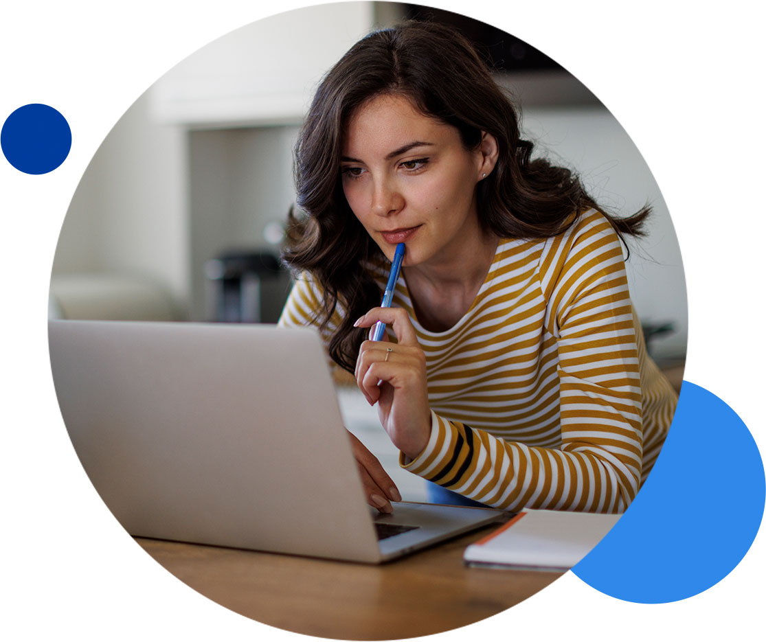 Woman in striped shirt working on a laptop with pen in hand